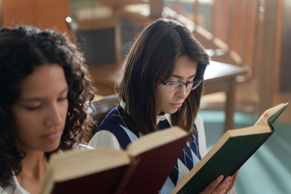 Two students reading books together