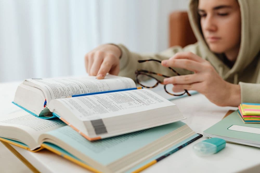 A teenager revising from open textbooks